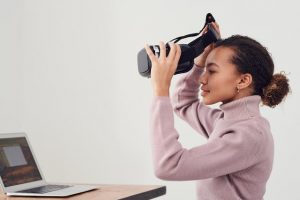 Jeune femme qui met un casque à réalité virtuelle pendant son travail