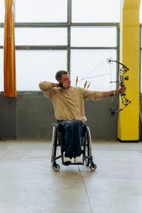 homme handicapé qui tir à l'arc dans un gymnase